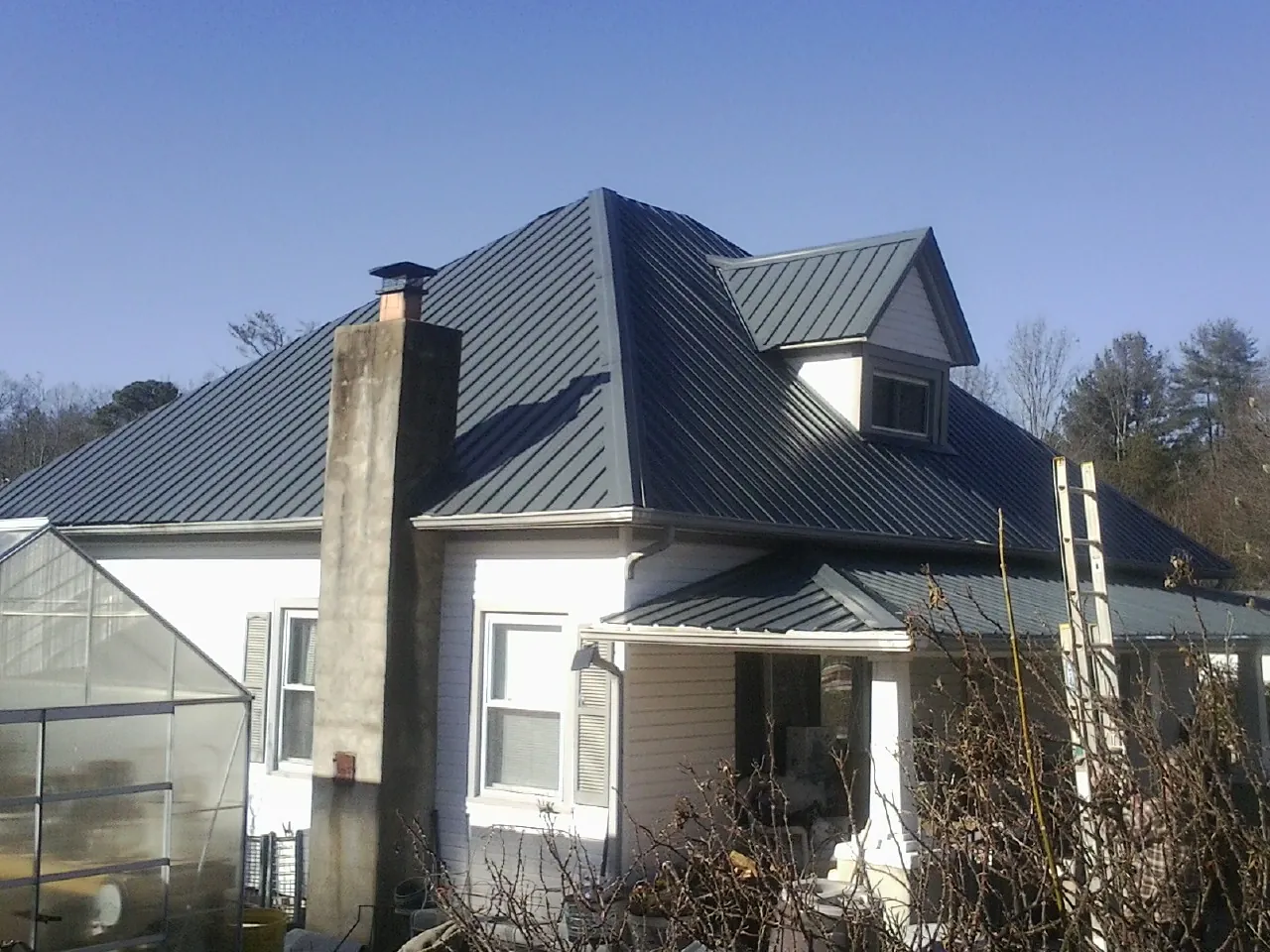 Dark blue standing seam metal roof on a white farmhouse with dormer — Slate & Tile Roof Repair by Roofing Brothers in Dalbo