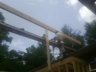 Carpenter setting a ridge beam over a new addition frame — Ice Dam Removal by Roofing Brothers in Dalbo