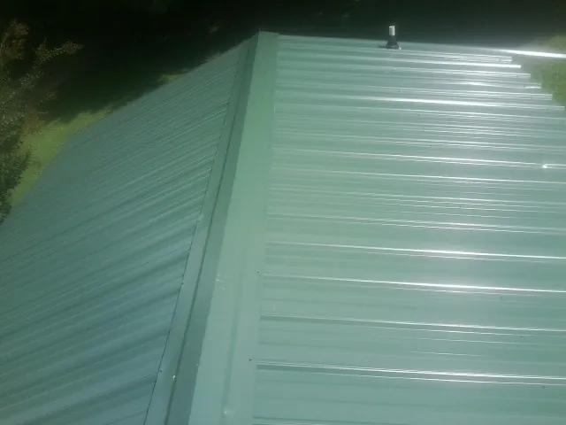 New green metal panels meeting at the ridge of a roof — Flat Roof Repair work by our crew in Dalbo