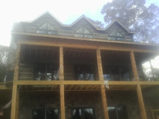 Dormers and porch framing on a large log home under construction — Roof Coating work by our crew in Dalbo