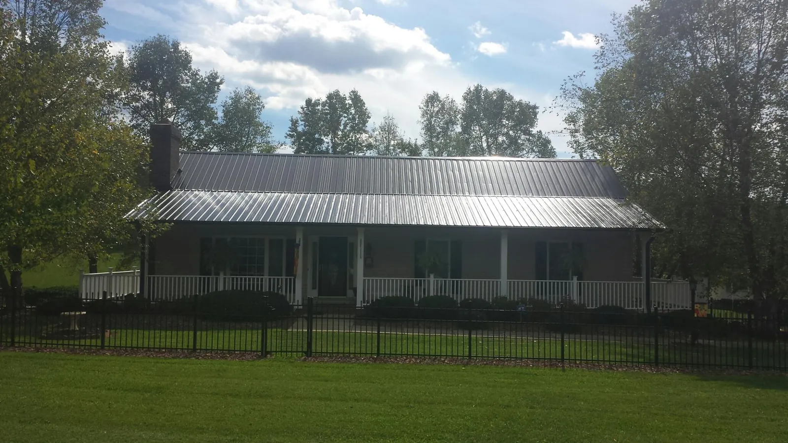 Gray metal roof on a brick ranch with a full width front porch — Gutter Guard Installation work by our crew in Dalbo